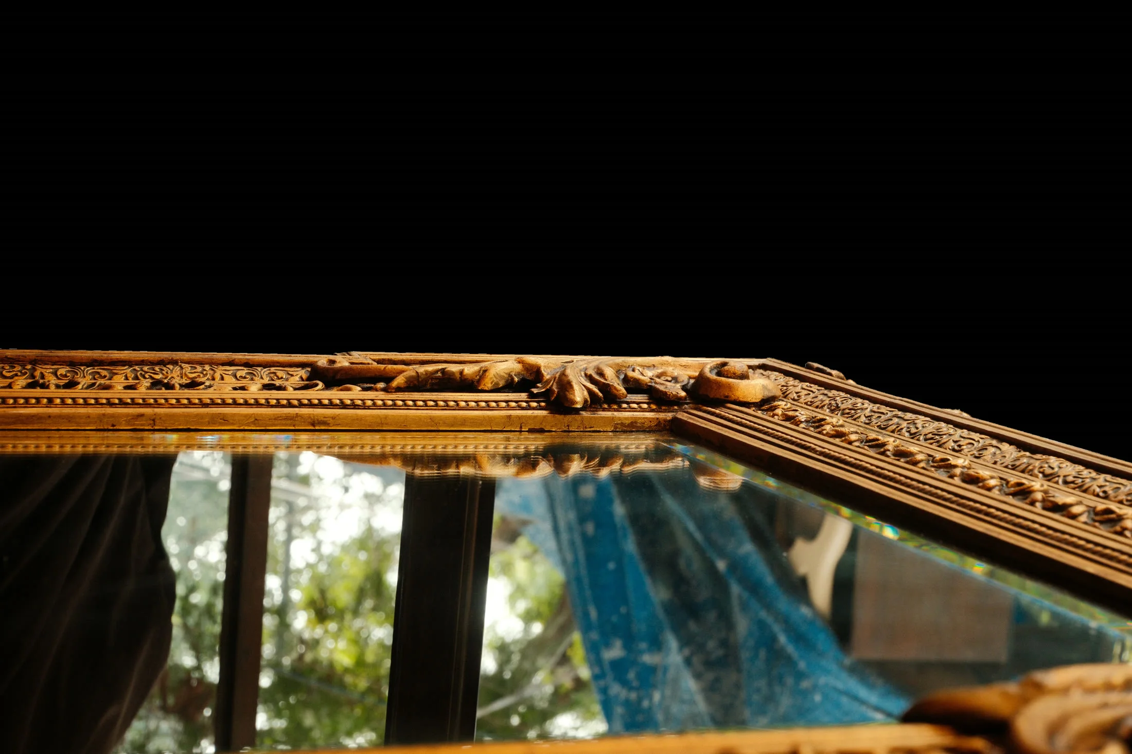 A teak-framed mirror among the stacked furniture of the market
