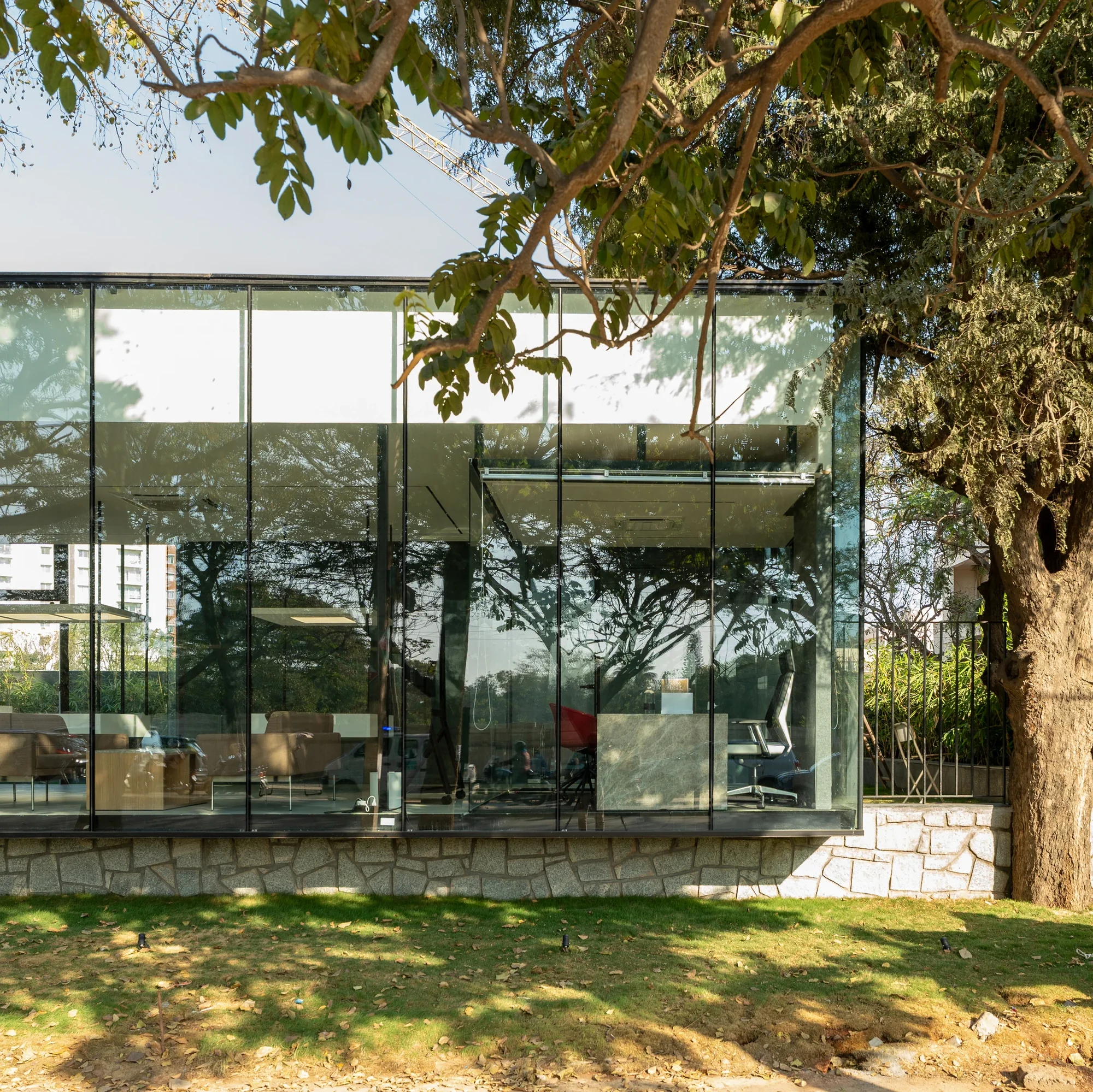 The realized glass pavilion among campus greenery