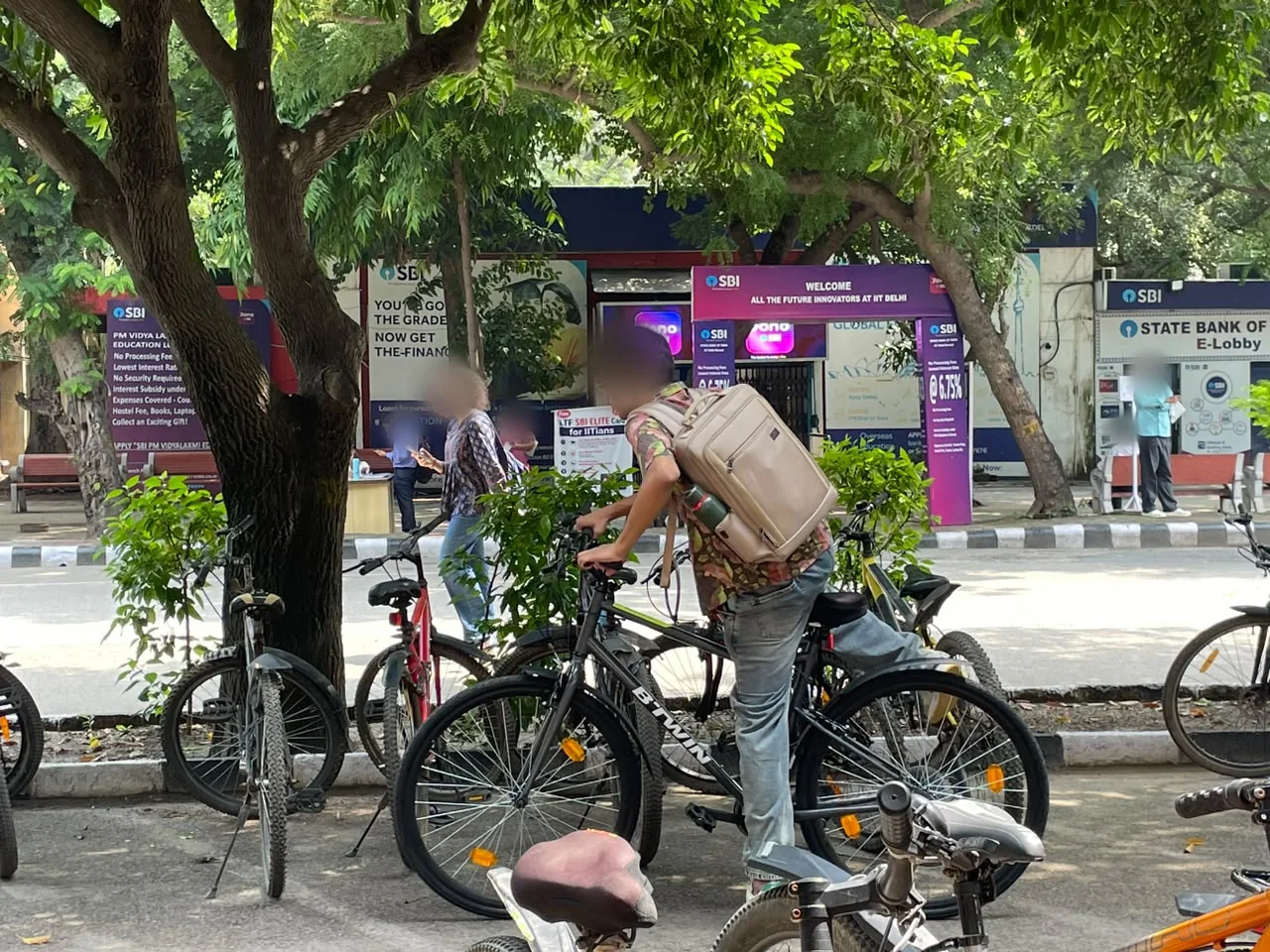 A rider astride a cycle at the northern end of the lane, beside the main road and the SBI frontage