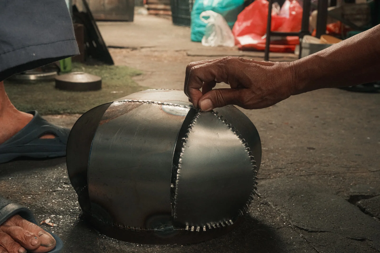 A black alms bowl in the maker's hands