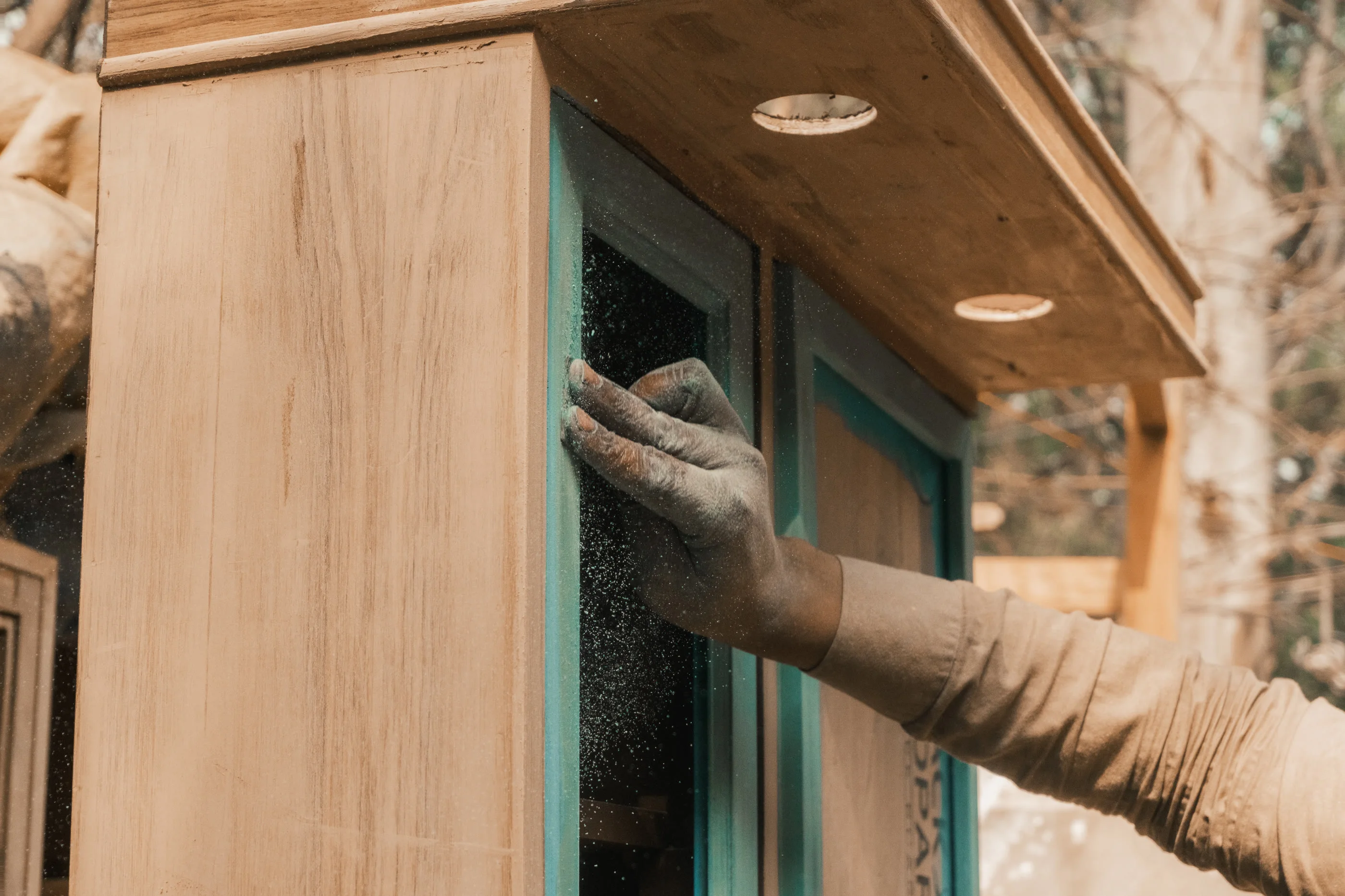 A dust-covered hand resting on a stripped wooden cabinet in the market