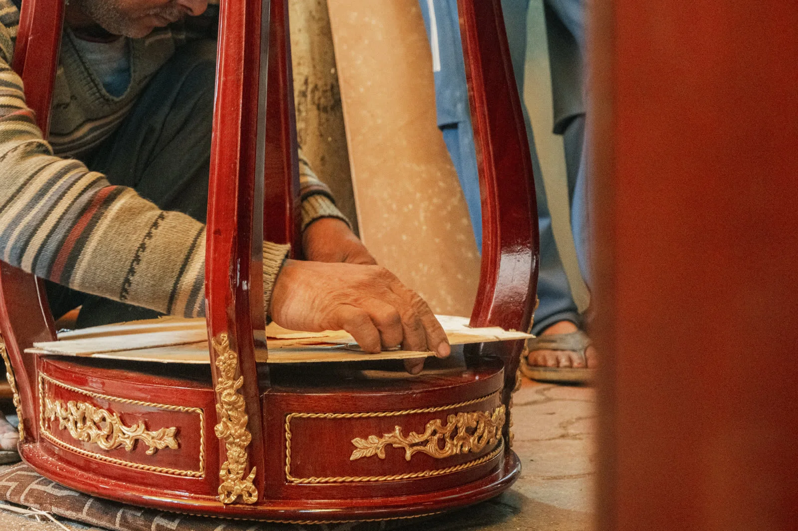 A craftsman reassembling an ornate lacquered vitrine