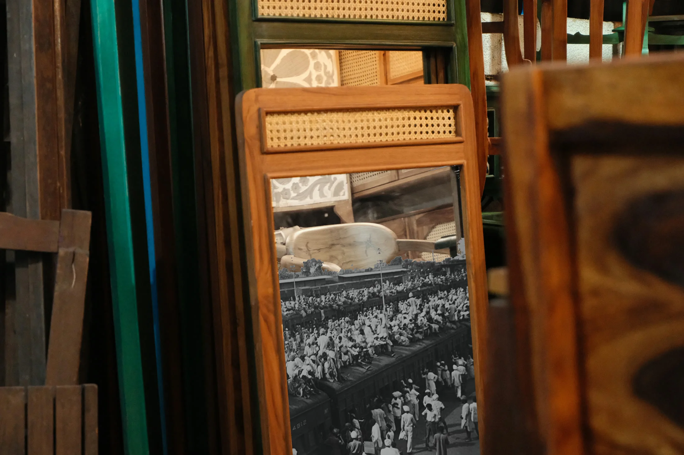 A Partition-era archival photograph reflected in a teak mirror among the furniture