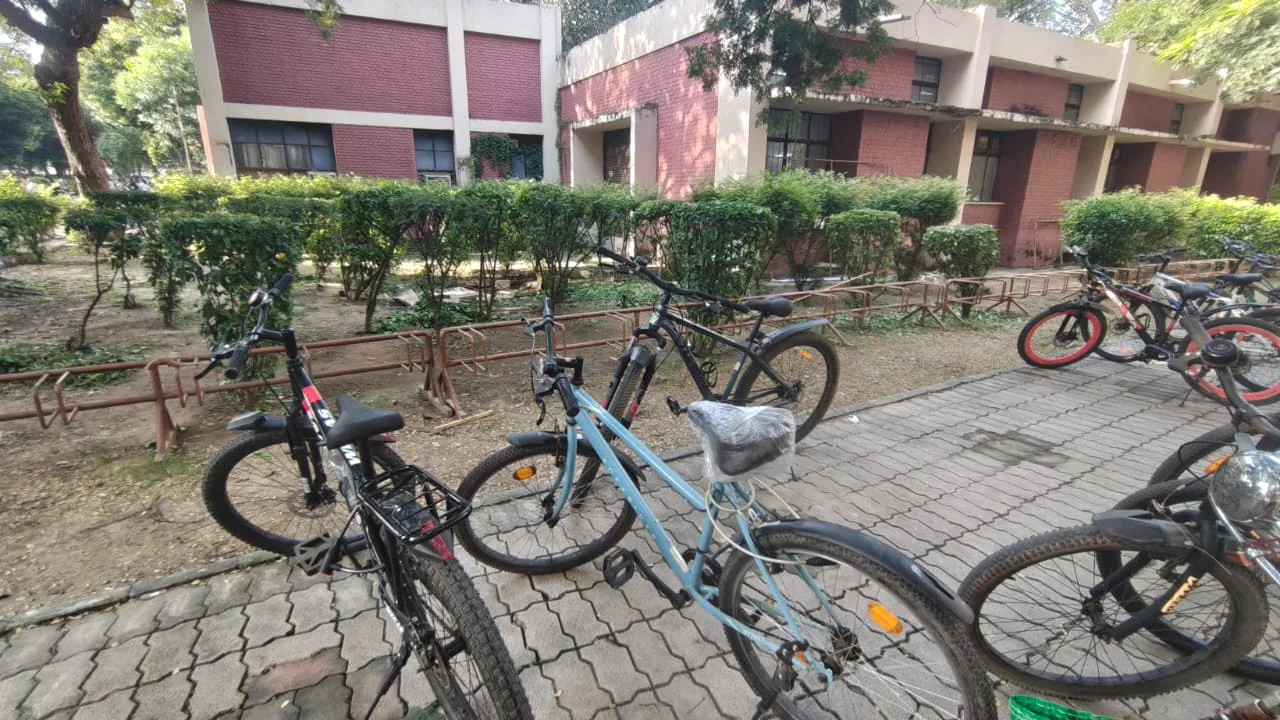 Bars set back behind a planted hedge, with cycles parked on the paving in front of them