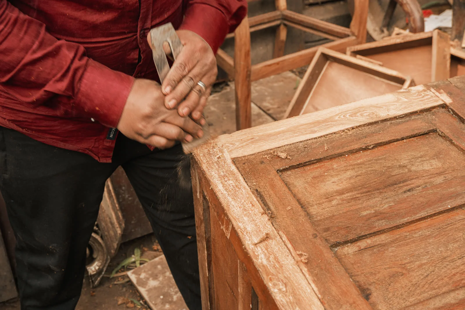 A craftsman using makeshift tools on a piece of furniture