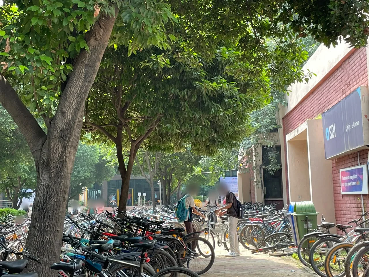 The lane beside the SBI building, two riders positioning their cycles in a narrow gap between the rows