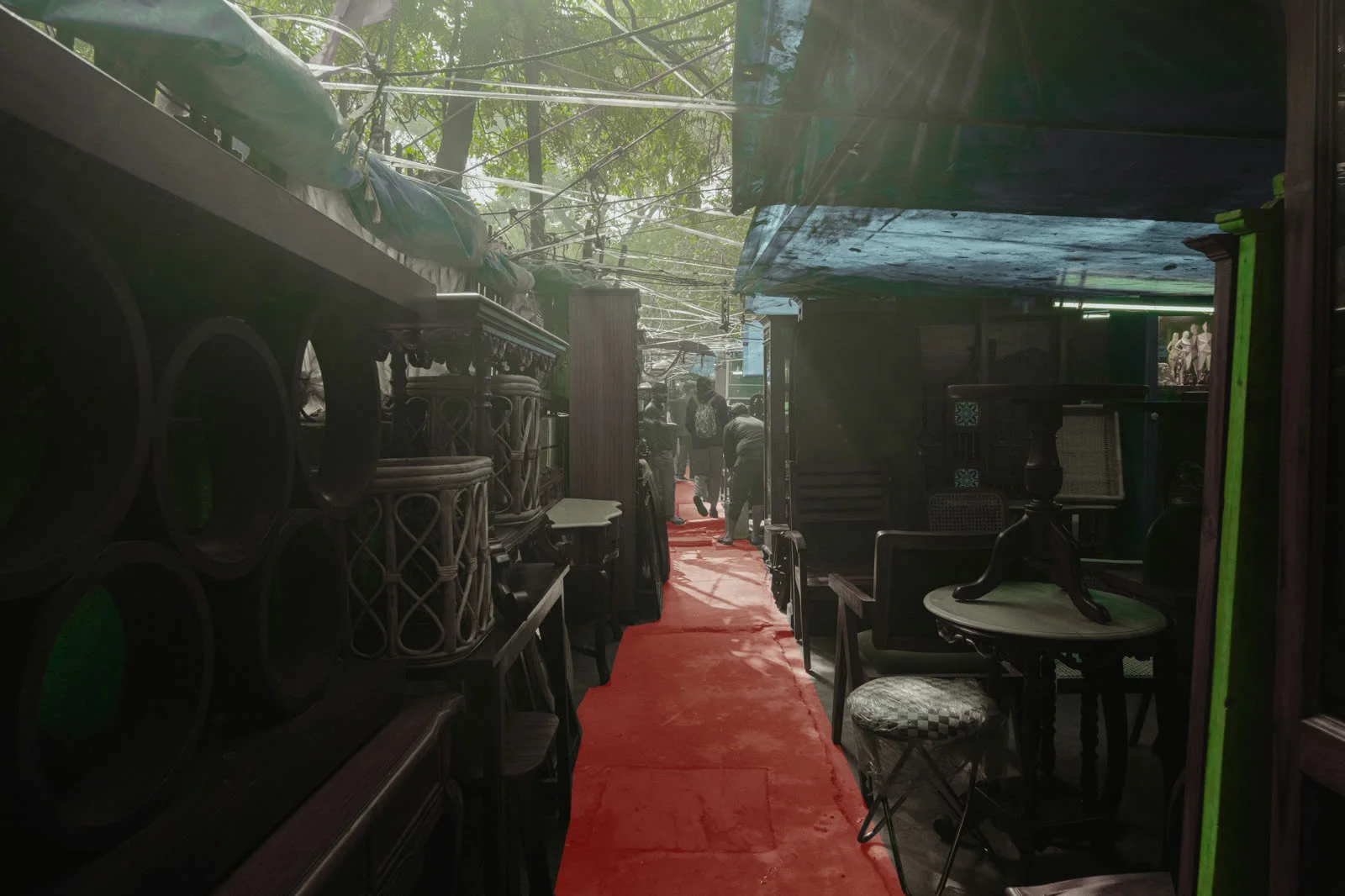 A narrow aisle with a red runner cut between stacks of furniture