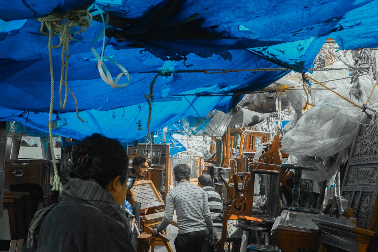 Blue tarpaulin sheets stretched overhead as a makeshift ceiling