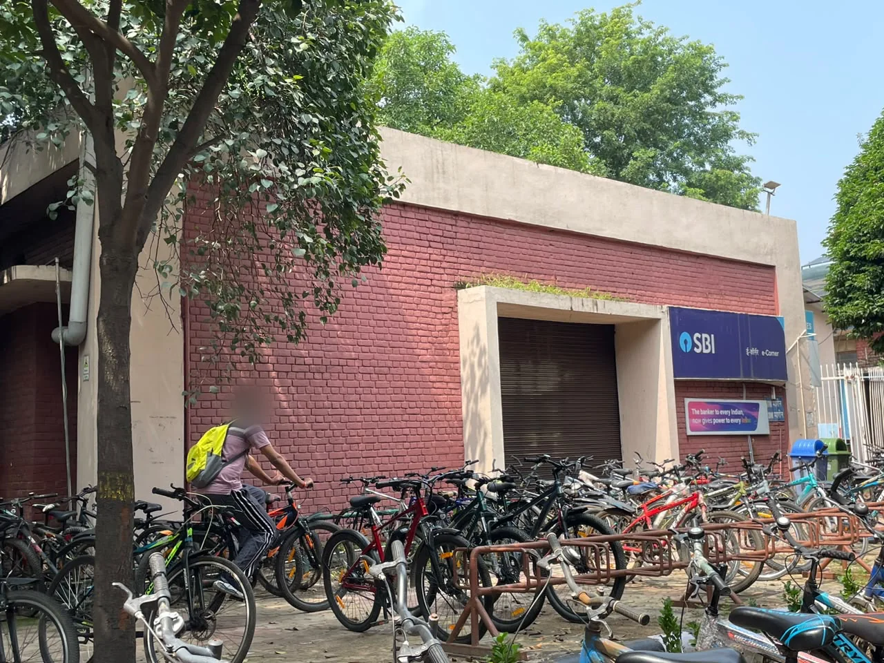 A rider passing the SBI building at 11.55 am, the bay of bars in front of it crowded with cycles
